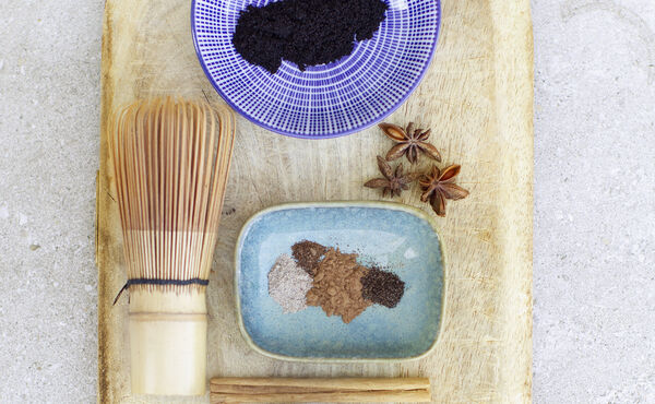 bambuvisp, lönnsirap, stjärnanis, vaniljpulver, kanelstång och kryddor på en träbricka